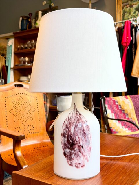 «Symmetrisk» glasslampe, vintage eller fra danske Holmegaard. Formgitt av Michael Bang på 1980-tallet. Plommefarget mønster foran og gullfarget kant nederst/på sokkel. Moderne stikk. Selve bordlampen måler H 28 cm, inkl skjerm 51 cm. Ø fot 16 cm. Pris inkl skjerm: 1900 kr. Kjøpe nå med Vipps? Send melding. Må hentes, sendes ikke.